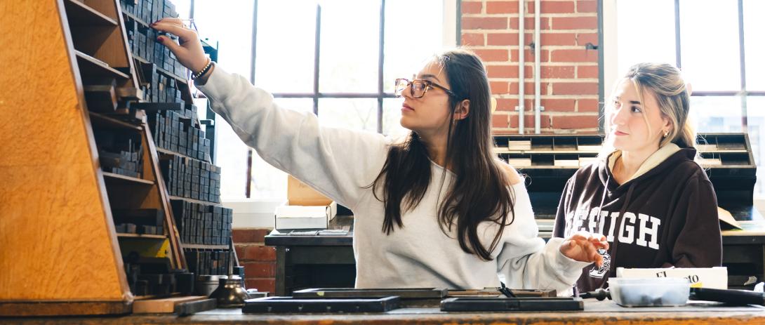 Students in a print shop pick out letters for the press.